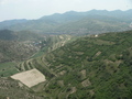 #4: View looking back towards the main road, which is hidden from view, but runs from left to right near the red-roofed building in the distance